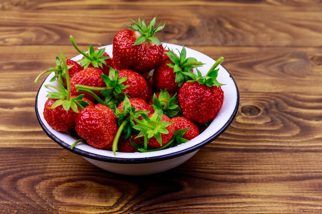 Fraise mûre fraîche dans un bol blanc sur une table en bois