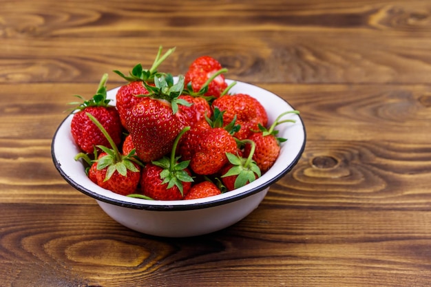 Fraise mûre fraîche dans un bol blanc sur une table en bois