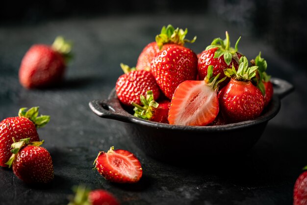 Fraise mûre fraîche dans un bol sur fond sombre