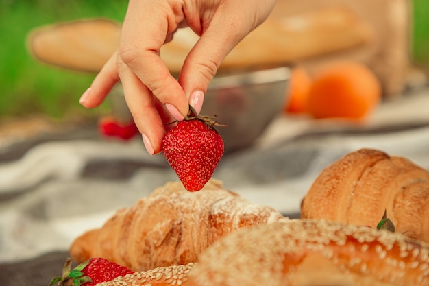 Fraise Mûre Juteuse En Jeune Femme Main Concept De Pique-nique D'été Croissants Et Bagels Sur Bois