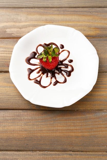 Fraise mûre rouge avec du chocolat sur une table en bois