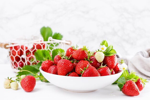 Fraise sur plaque avec brindilles et feuilles sur fond blanc