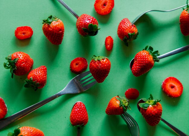 Fraise de printemps et fourchettes sur fond vert. Vue ci-dessus