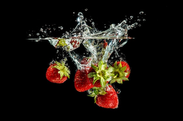 Fraise tombant pure dans l'eau avec éclaboussures