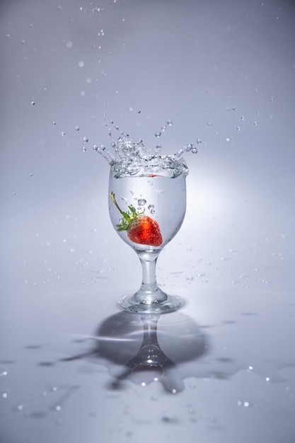 La fraise tombe dans un verre d'eau