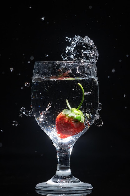 La fraise tombe dans un verre d'eau