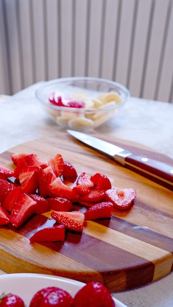 Photo fraise tranchée sur planche de bois préparant un smoothie ou un milk-shake à la fraise et à la banane