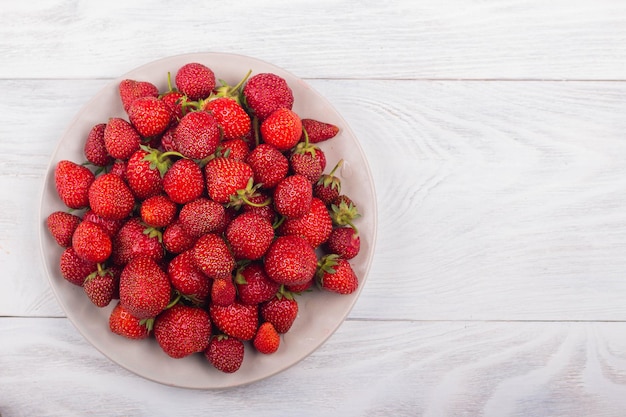 Fraises sur une assiette sur un fond en bois blanc