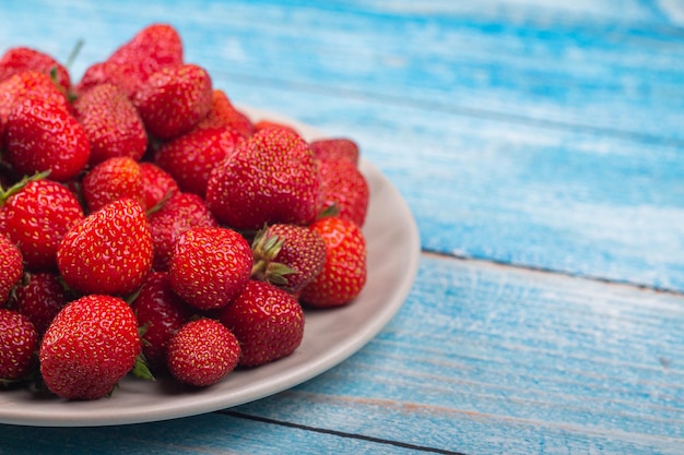 Fraises sur une assiette sur un fond en bois bleu