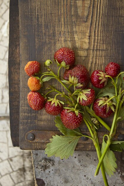 Photo des fraises biologiques fraîches rouges sur une planche à couper en bois rugueuse, nourriture végétarienne naturelle crue