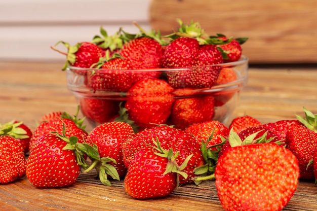 Fraises biologiques rouges mûres sur fond en bois marron.