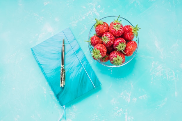 fraises et cahier, stylo doré sur une table