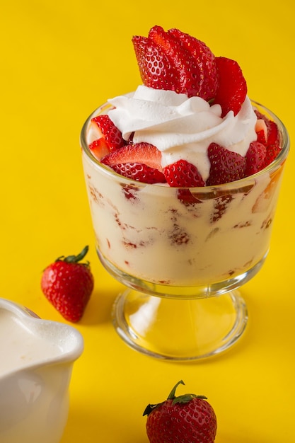 Des fraises avec de la crème dans une tasse en verre.