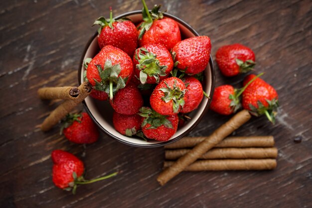 fraises dans une assiette d'argile avec des bâtonnets sucrés tubes de chocolat