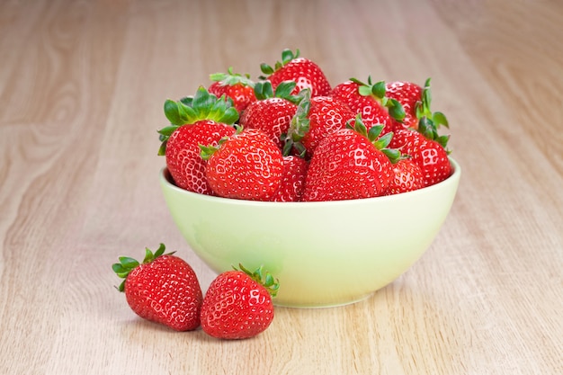 Fraises dans une assiette sur la table en bois