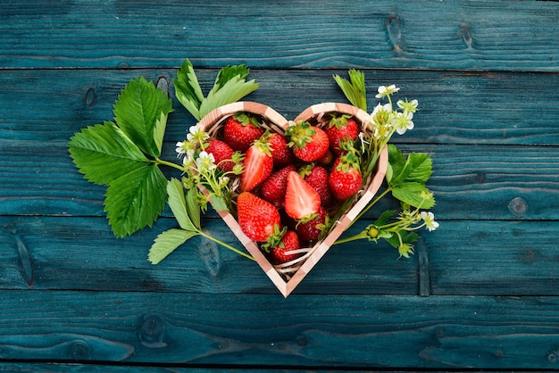 Fraises dans une boîte en forme de coeur Sur un fond en bois Vue de dessus Espace de copie