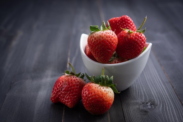 Photo fraises dans un bol en céramique belles fraises fraîches sur une table en bois jus de fraise