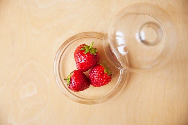 Fraises dans un bol en verre sur fond en bois