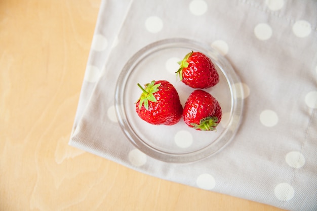 Fraises dans un bol en verre et pois à la serviette beige