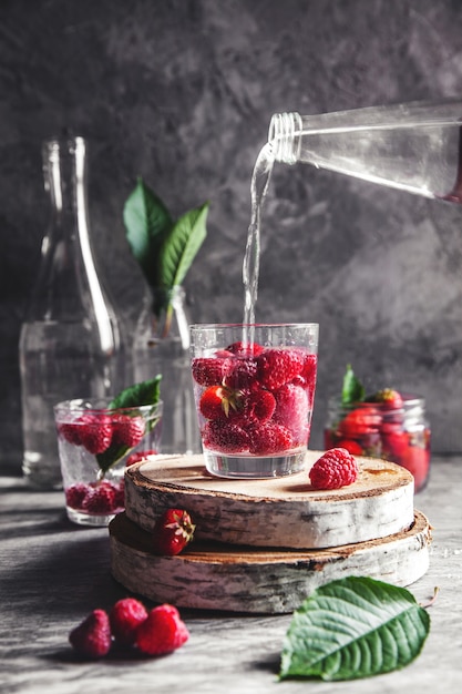 Photo fraises dans l'eau sur fond gris foncé. nourriture saine, fruits. un bouquet de fleurs comme décoration