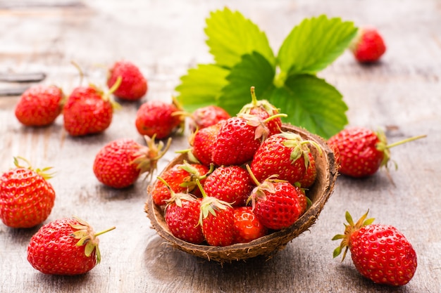 Fraises dans un petit bol et sur une table en bois