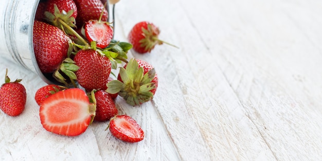 Fraises dans un seau sur une table en bois blanc