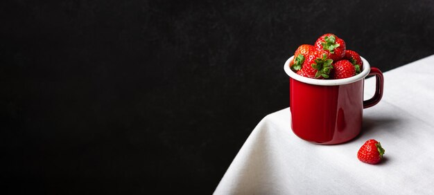 Des fraises dans une tasse d'émail avec un espace de copie