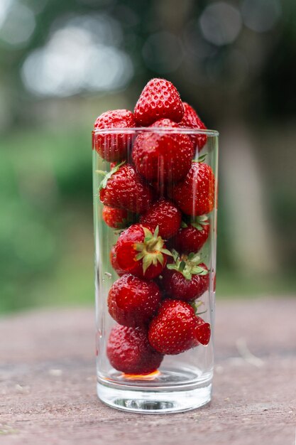 Fraises dans un verre dans le jardin sur une table en bois