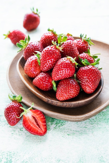 Fraises délicieuses mûres fraîches dans un bol en bois sur un fond en bois vert