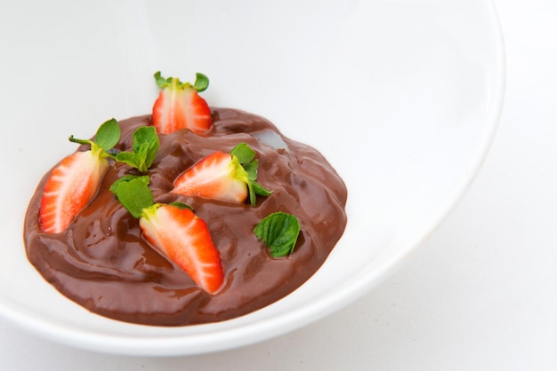 Fraises enrobées de chocolat sur une assiette sur fond blanc