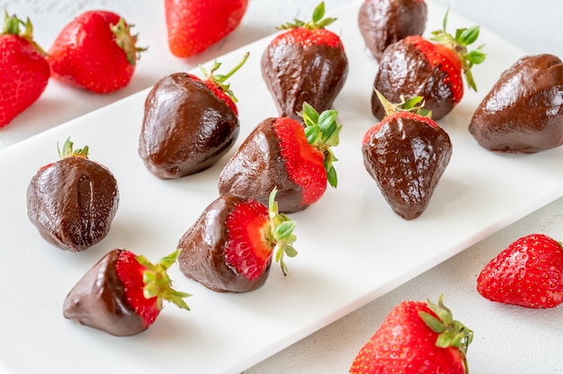 Fraises enrobées de chocolat sur l'assiette de service blanche