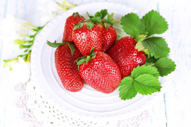 Fraises avec feuilles sur plaque sur fond de bois