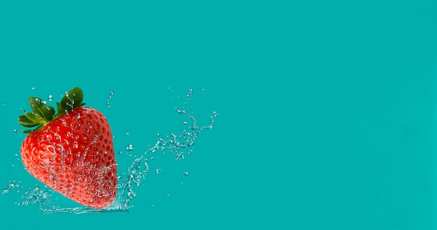 Fraises sur fond turquoise dans des éclaboussures d'eau