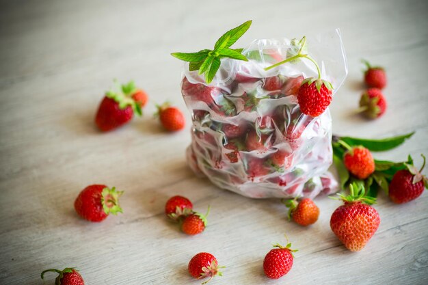 fraises fraîches congelées dans un sac sous vide sur une table en bois