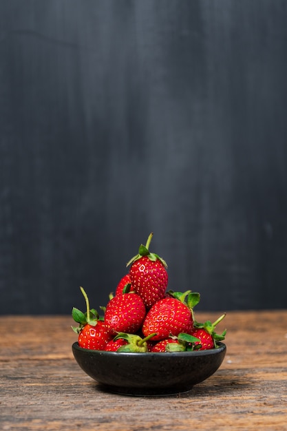 Fraises fraîches dans un bol sur une table en bois avec scène discrète Fraise avec espace blanc