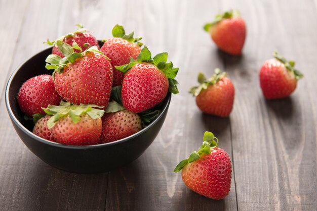 Fraises fraîches dans un bol sur une table en bois.