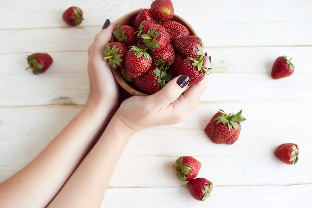 Fraises fraîches dans les mains de la femme