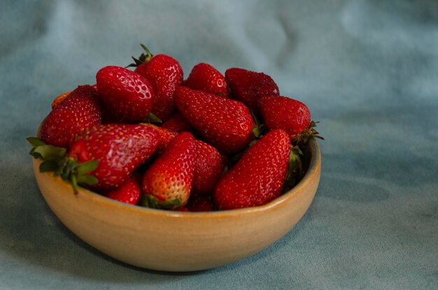 fraises fraîches dans un récipient en céramique avec un fond naturel fruits plus naturels