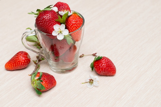 Fraises fraîches dans une tasse en verre sur une table en bois