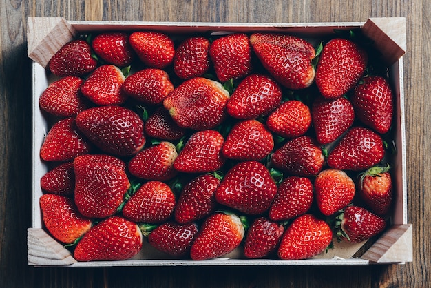 Fraises fraîches et juteuses dans une boîte en bois