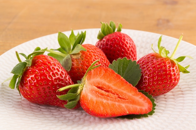 Fraises fraîches sur plaque blanche sur table en bois