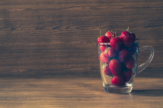 Fraises fraîches en verre sur le fond de la table en bois.