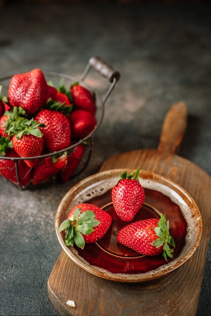 Fraises juteuses avec des feuilles sur fond rustique