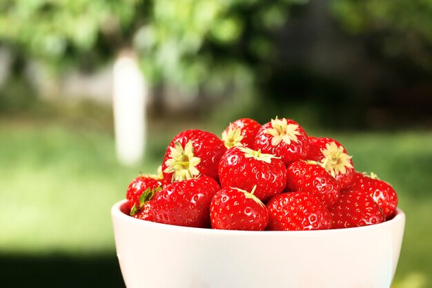 Fraises juteuses mûres dans un bol sur un fond en bois dans le jardin d'été. Vue de dessus