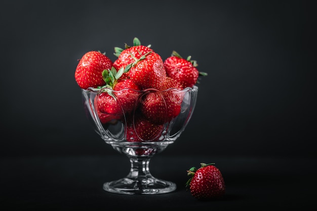 Fraises juteuses mûres dans un verre sur dark