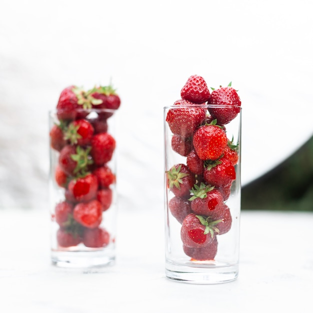 Fraises juteuses savoureuses dans un verre sur fond blanc