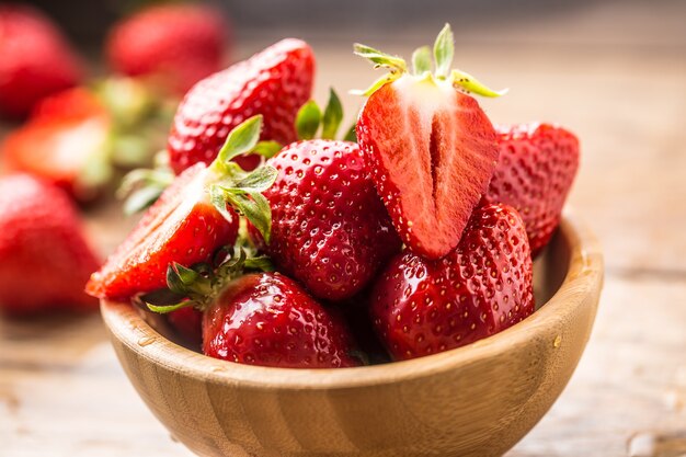 Fraises lavées juteuses dans un bol en bois sur la table de la cuisine.