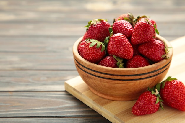 Fraises mûres dans un bol en bois sur une planche à découper