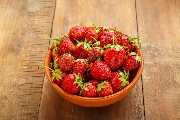 Fraises mûres dans un panier en osier sur un fond en bois.