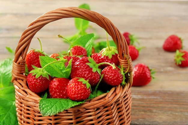 Fraises mûres dans un panier en osier sur une table en bois libre